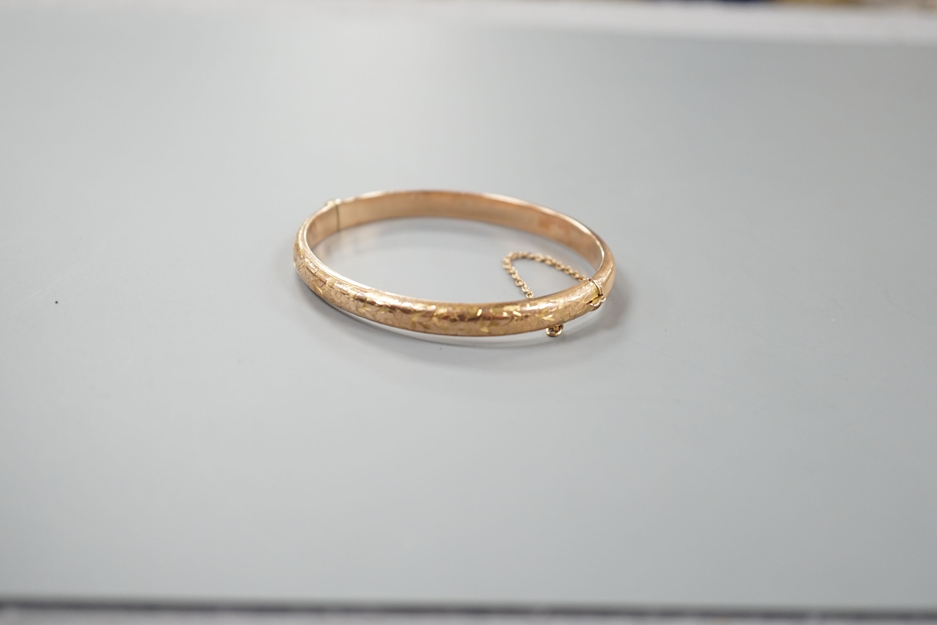 An engraved hollow 9ct gold bangle, 7.6 grams.